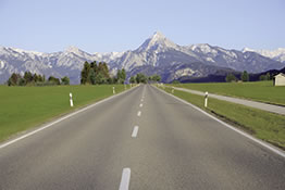 The image shows a street with mountains in the backround. 